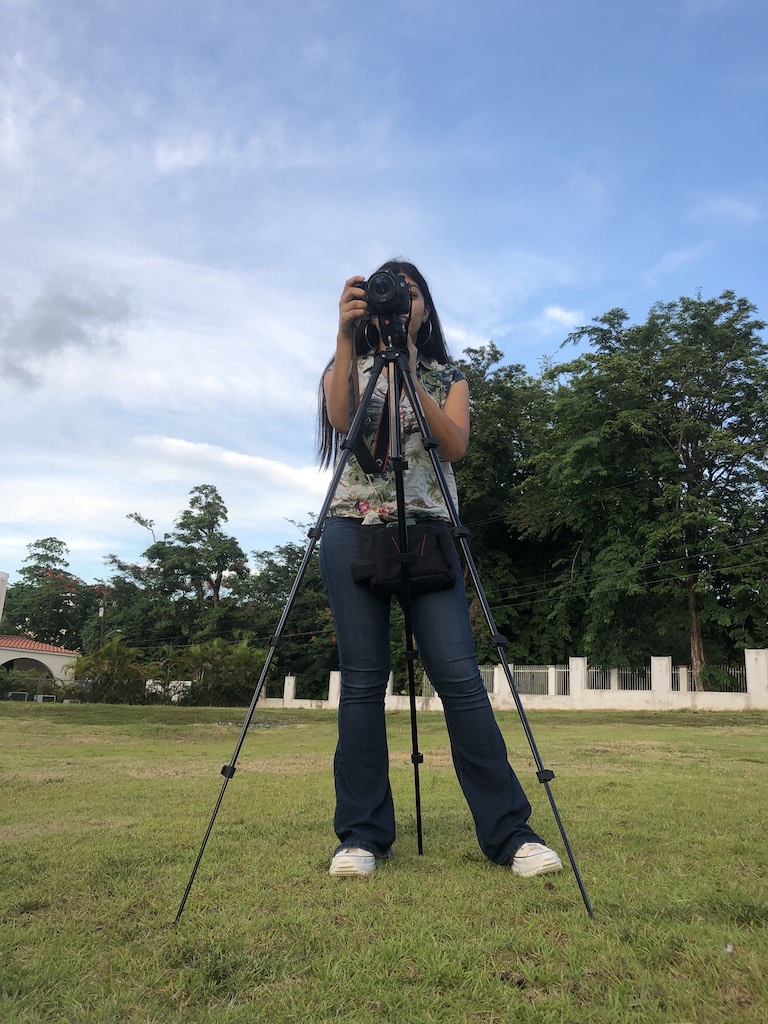 Isabella Gierbolini looking into a camera on a tripod while she films outside